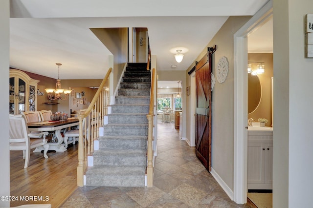 stairs with a barn door, sink, and a chandelier