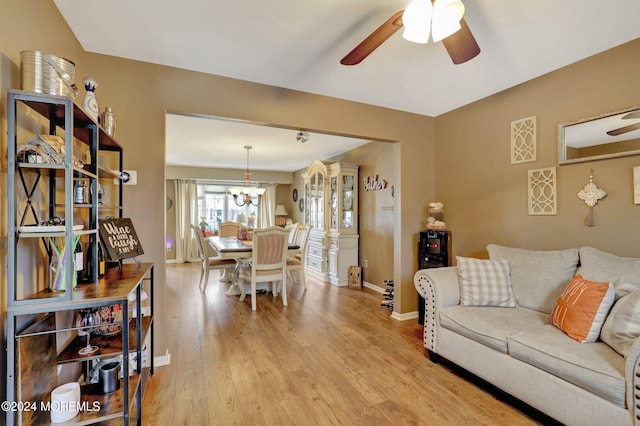 living room featuring ceiling fan with notable chandelier and light hardwood / wood-style floors