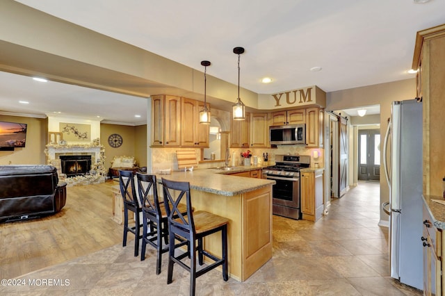 kitchen featuring pendant lighting, sink, a breakfast bar, stainless steel appliances, and kitchen peninsula