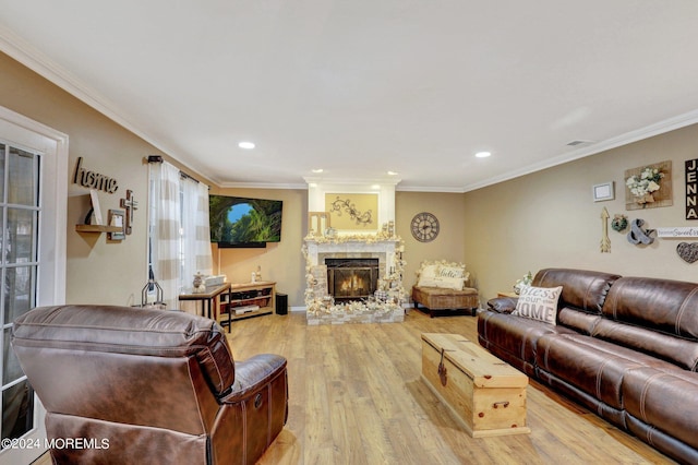 living room featuring a large fireplace, ornamental molding, and light hardwood / wood-style floors