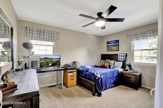 bedroom featuring multiple windows, light carpet, and ceiling fan