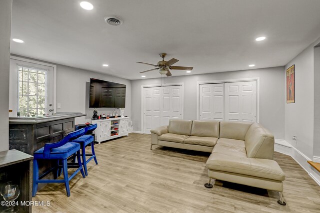 living room with ceiling fan, light wood-type flooring, and indoor bar