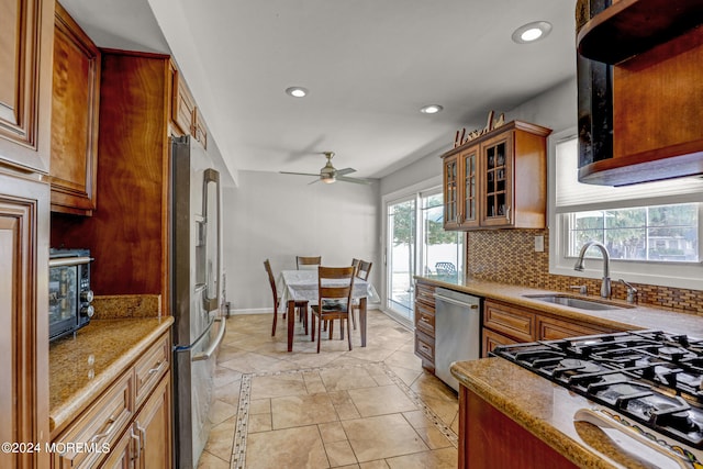 kitchen featuring light stone counters, ceiling fan, sink, appliances with stainless steel finishes, and backsplash