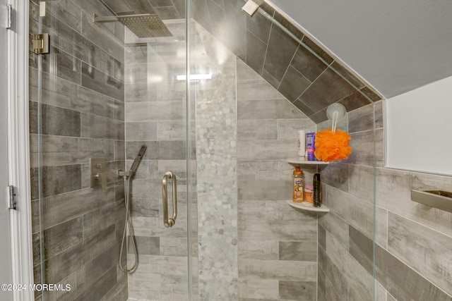 bathroom with a shower with shower door and vaulted ceiling