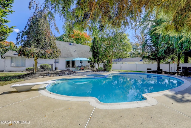 view of swimming pool with a diving board and a patio area