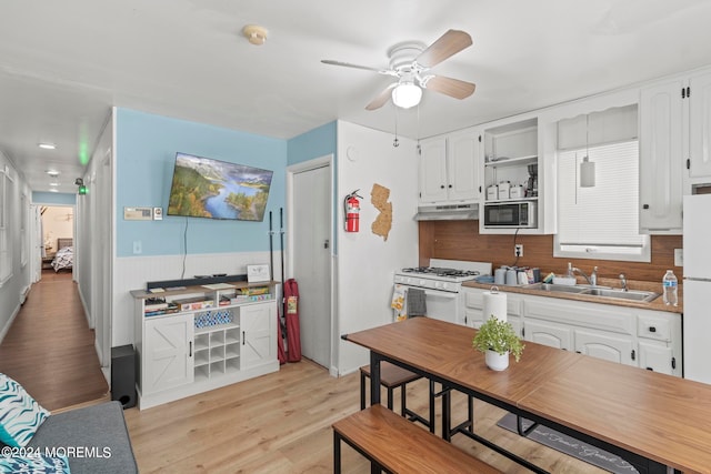 kitchen featuring white range with gas stovetop, light wood-type flooring, sink, and white cabinets