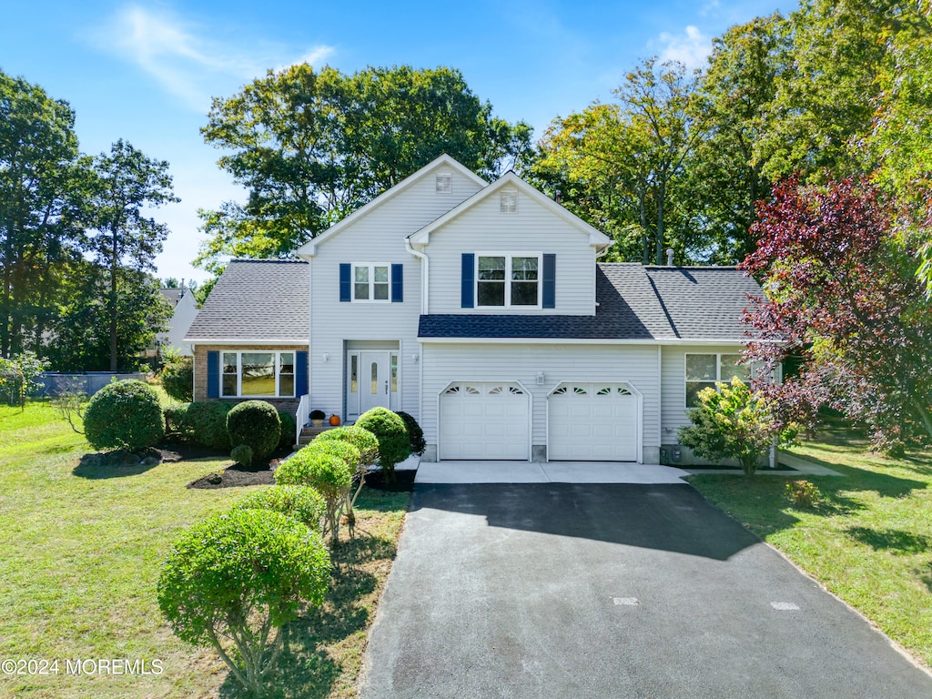 view of property featuring a garage and a front lawn