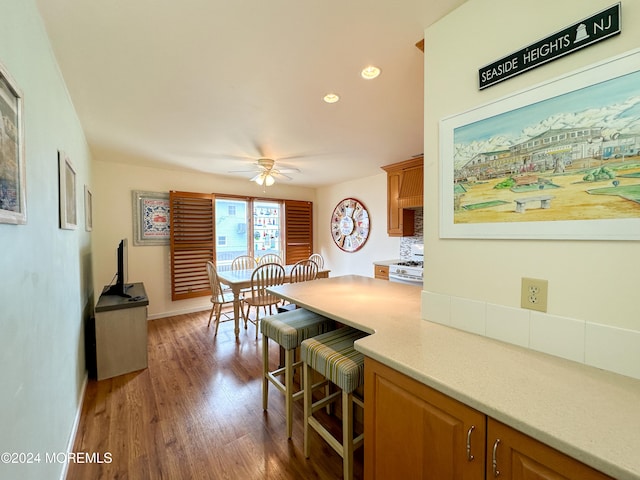 kitchen featuring white gas range, a kitchen bar, dark hardwood / wood-style flooring, and ceiling fan