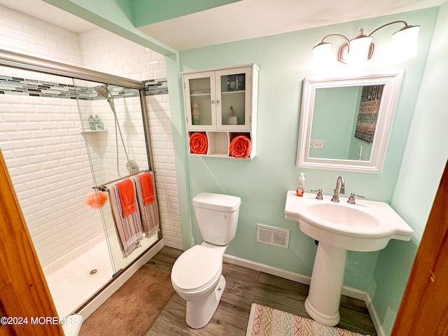 bathroom with wood-type flooring, toilet, and a shower with shower door