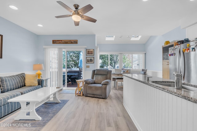 living room with ceiling fan, sink, and light hardwood / wood-style floors