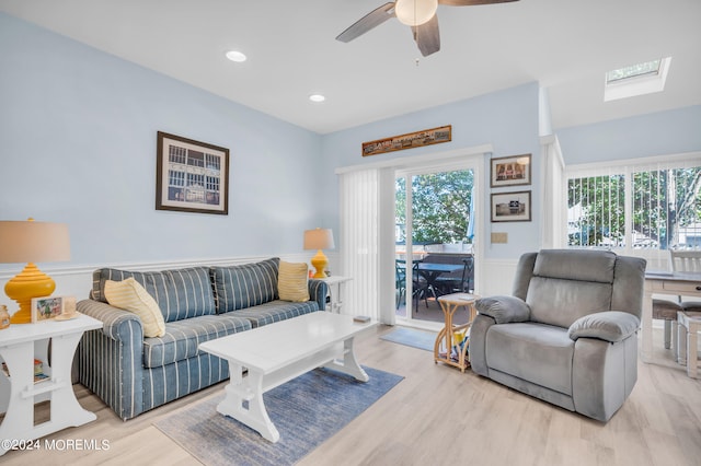 living room featuring a skylight, light wood-type flooring, and ceiling fan