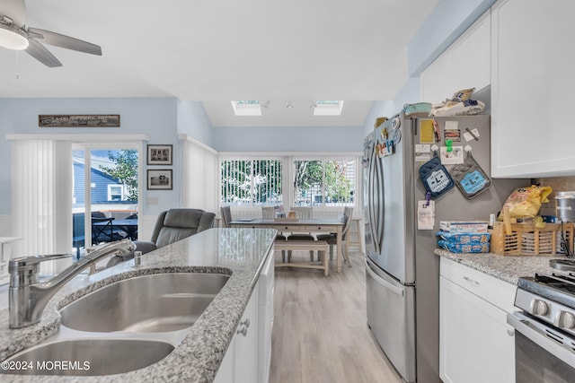 kitchen with light hardwood / wood-style floors, sink, stainless steel appliances, light stone countertops, and white cabinets