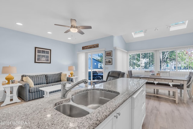 kitchen with light stone counters, sink, a wealth of natural light, and white cabinetry