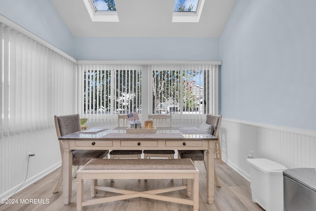 dining area featuring light wood-type flooring and lofted ceiling with skylight