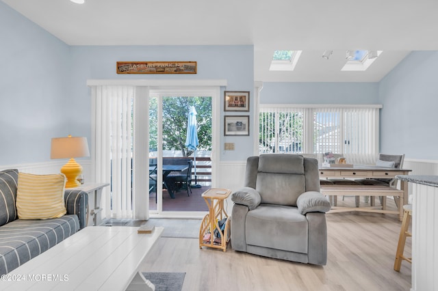 living room featuring vaulted ceiling with skylight and light hardwood / wood-style flooring