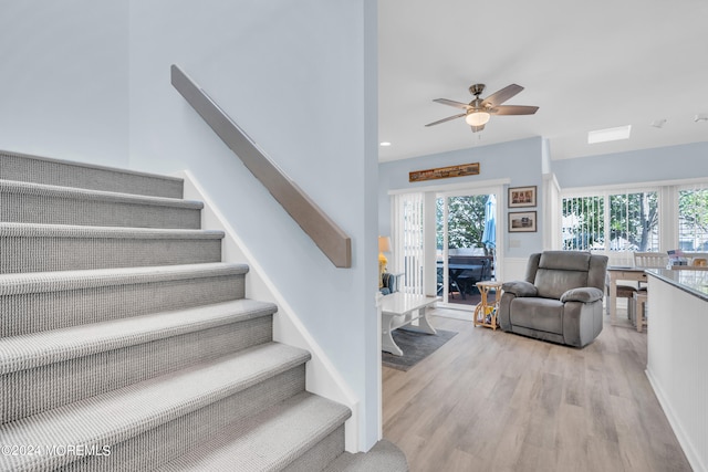 staircase featuring wood-type flooring and ceiling fan