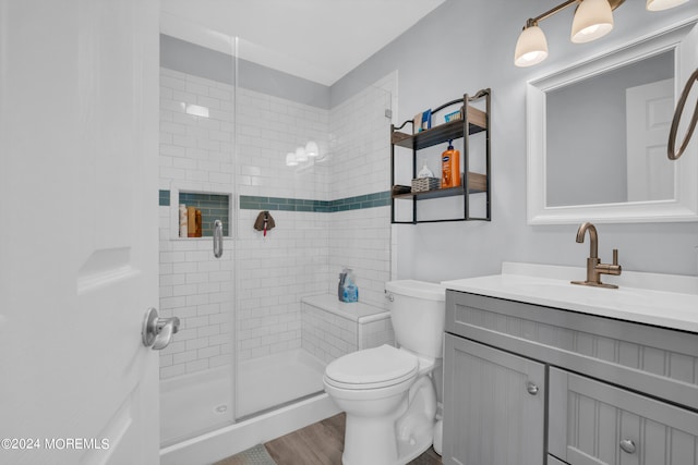 bathroom with wood-type flooring, a shower with door, vanity, and toilet