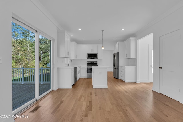 kitchen featuring decorative light fixtures, stainless steel appliances, light countertops, white cabinets, and a kitchen island