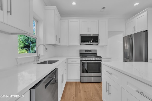 kitchen featuring appliances with stainless steel finishes, a sink, and white cabinets