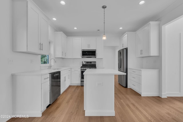 kitchen with pendant lighting, stainless steel appliances, light countertops, white cabinets, and a kitchen island