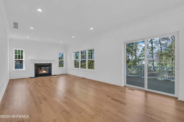 unfurnished living room with light wood-style floors, visible vents, plenty of natural light, and a fireplace with flush hearth