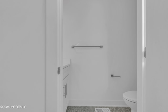 bathroom with toilet, vanity, visible vents, and baseboards