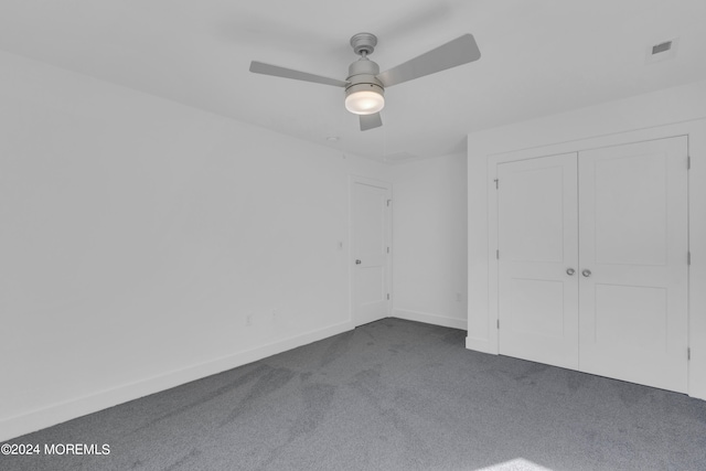 unfurnished bedroom with dark colored carpet, a closet, visible vents, a ceiling fan, and baseboards