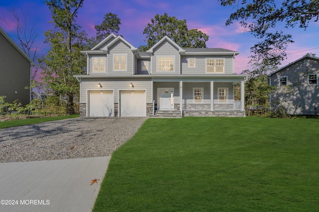 view of front of house with a porch, a garage, a yard, stone siding, and driveway