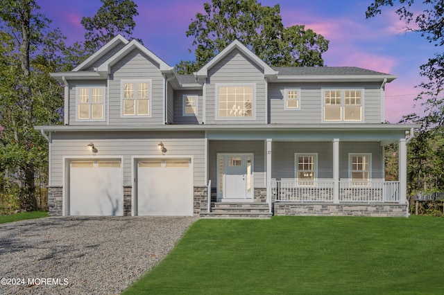 view of front of house featuring a garage, a lawn, and a porch