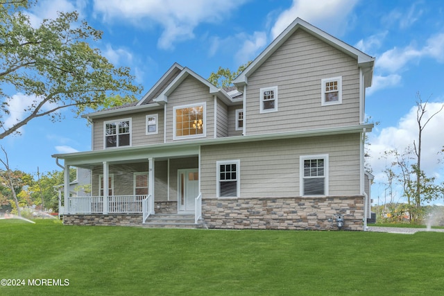 view of front of house featuring covered porch, stone siding, and a front yard