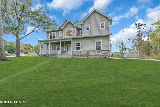 view of front facade featuring covered porch, stone siding, and a front lawn