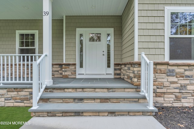 entrance to property featuring covered porch and stone siding