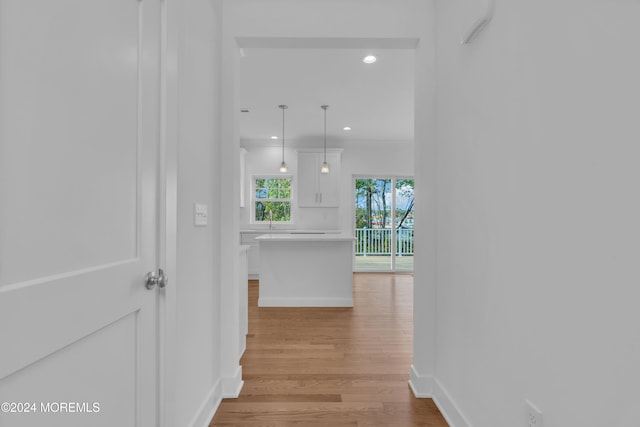 hallway with ornamental molding, recessed lighting, baseboards, and light wood finished floors