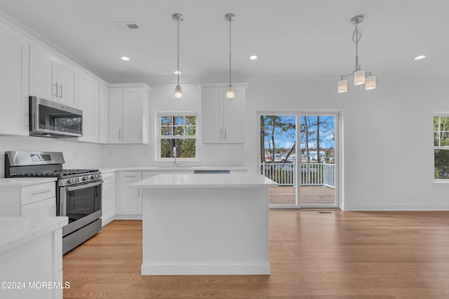 kitchen with stainless steel appliances, light countertops, decorative light fixtures, and white cabinetry