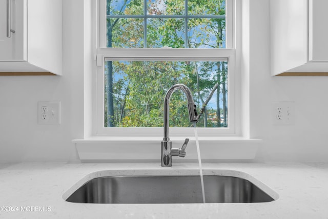 room details with light stone counters, a sink, and white cabinets