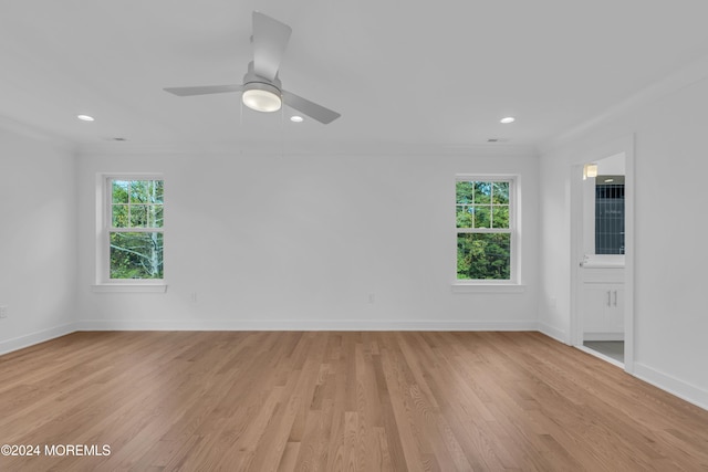 empty room featuring baseboards, ornamental molding, light wood-style flooring, and a healthy amount of sunlight