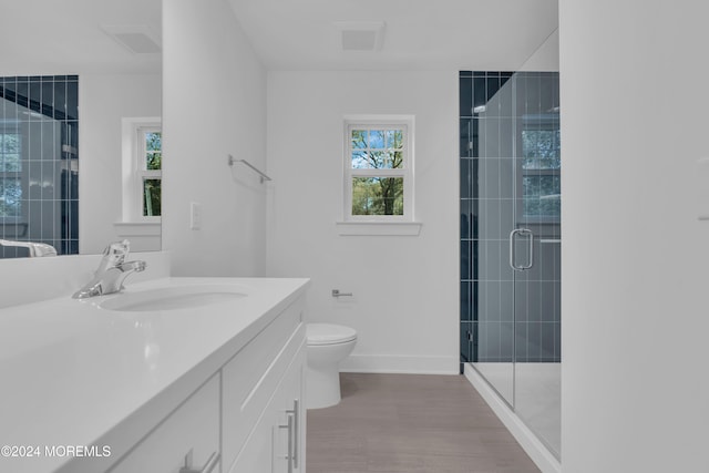 bathroom with toilet, a stall shower, vanity, wood finished floors, and baseboards