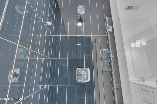 full bath with visible vents, vanity, and tiled shower