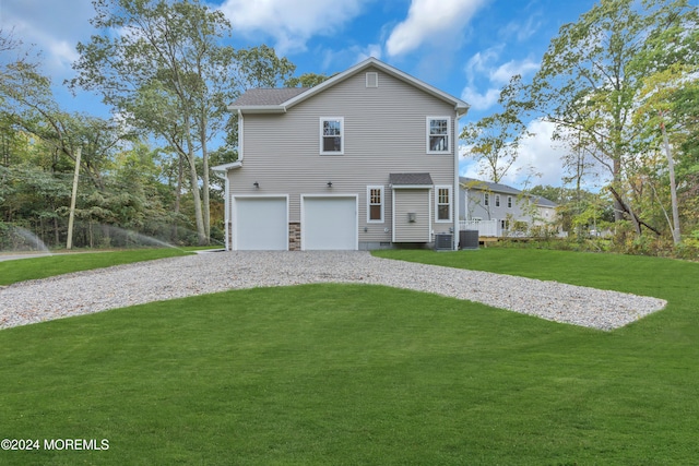 back of property featuring a garage, driveway, and a yard