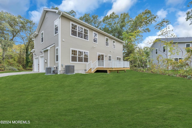 rear view of property featuring a garage, central AC unit, a deck, and a lawn