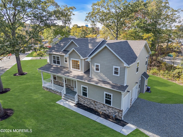 view of front of house with a porch, a front yard, and stone siding