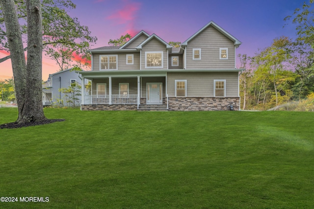 view of front facade featuring a porch, stone siding, and a front lawn