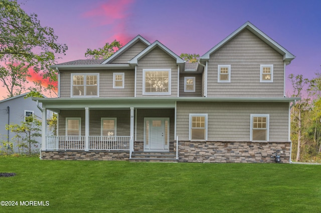 view of front of property with a porch, stone siding, and a front lawn