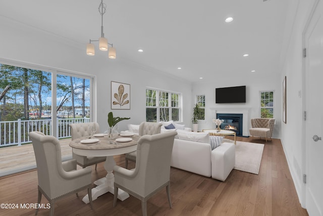 dining room with recessed lighting, ornamental molding, a glass covered fireplace, wood finished floors, and baseboards