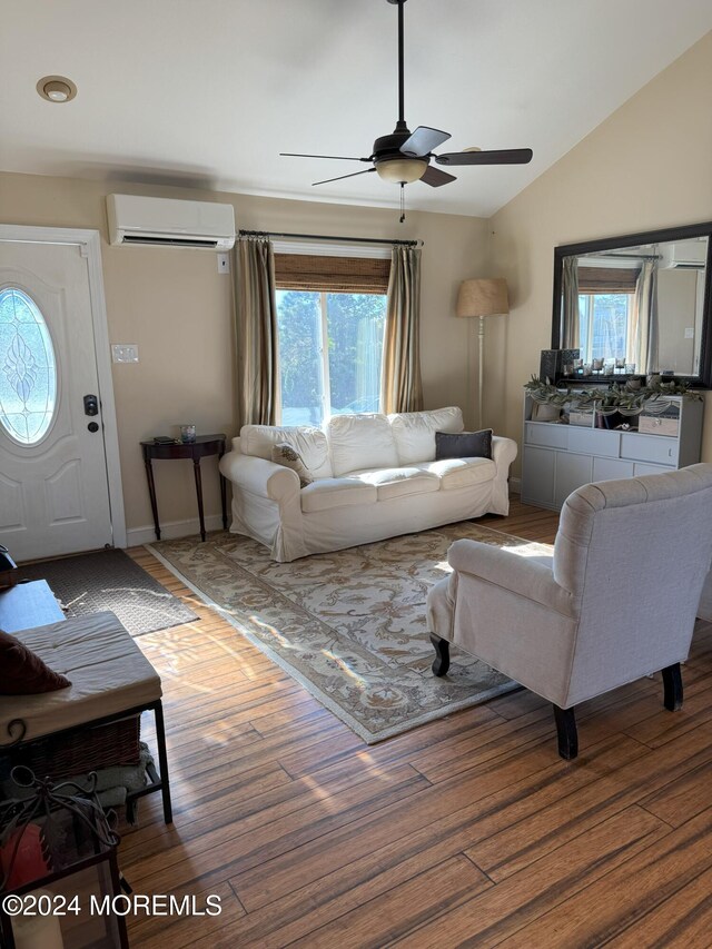 living room featuring an AC wall unit, vaulted ceiling, light hardwood / wood-style flooring, and a wealth of natural light