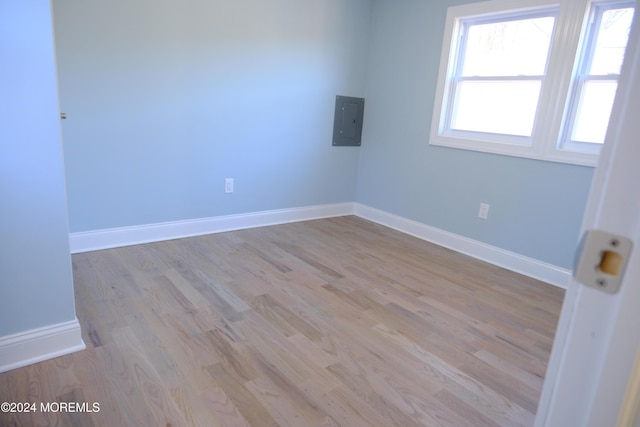 spare room with electric panel and light hardwood / wood-style floors