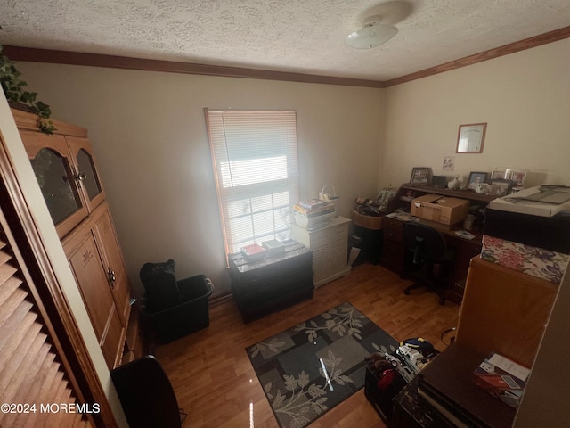 office space featuring a textured ceiling, light wood-type flooring, and crown molding