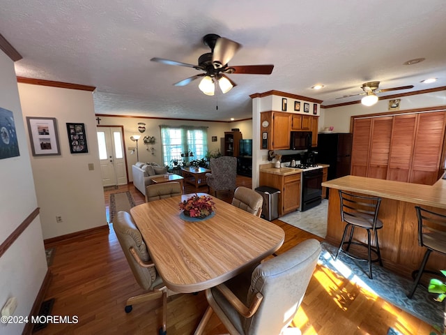 dining area with ornamental molding, ceiling fan, a textured ceiling, and light hardwood / wood-style flooring