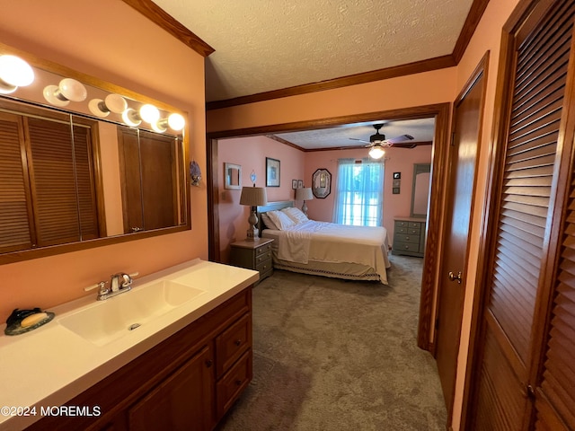 carpeted bedroom with crown molding, ceiling fan, sink, and a textured ceiling