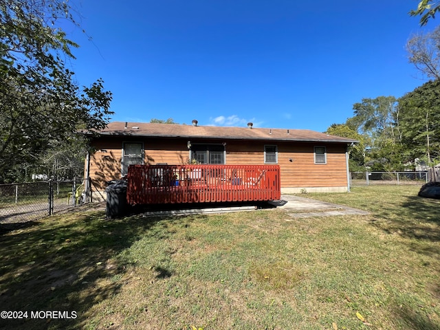 rear view of property featuring a lawn and a deck